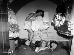 three women are laying on the bed and one woman is standing up in front of them