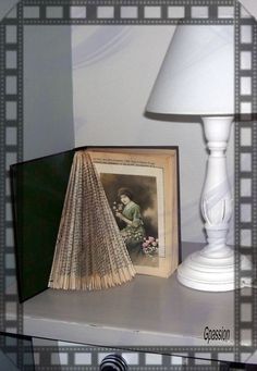 an open book sitting on top of a shelf next to a lamp and framed photograph