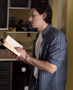 a man standing in a kitchen reading a book