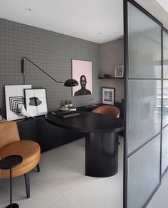 an office with a black table and brown chairs in front of a glass door that leads to another room