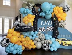 a car themed birthday party with balloons and race cars on the wall in front of it