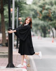 a woman leaning against a pole on the street