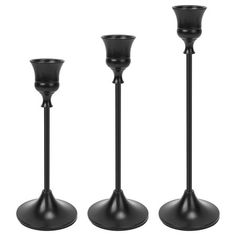 three black candlesticks sitting next to each other