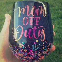 a hand holding up a wine glass with the words mom off duty painted on it