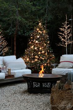 an outdoor living room decorated for christmas with lights on the trees and white couches