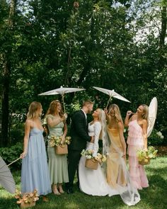 a group of people standing next to each other holding umbrellas in front of trees