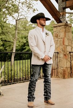 a man wearing a cowboy hat standing in front of a building