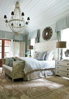 a bedroom with a chandelier hanging from the ceiling and a bed in front of it