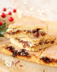 two pieces of dessert sitting on top of a wooden cutting board next to a holly branch