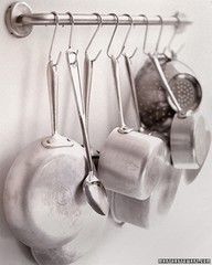 pots and pans are hanging from hooks on the wall in this black and white photo