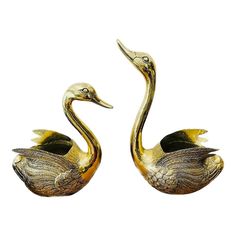 two brass swan figurines sitting next to each other on a white background,