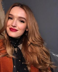 a close up of a person with long hair wearing a scarf and smiling at the camera