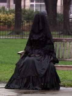 a woman in a black dress sitting on a bench