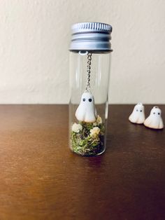 three small white ghost figurines in a glass jar