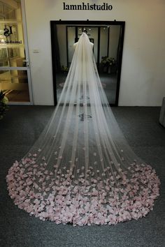 a wedding veil with pink flowers on the floor in front of an entrance to a building