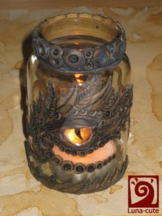 a glass jar with a candle inside sitting on a table