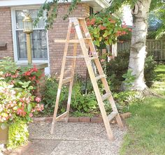 a wooden ladder sitting in front of a house next to a flower bed and potted plant