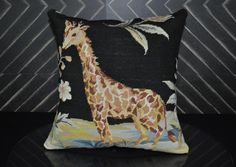 a giraffe on a black background is featured in this decorative pillow with feathers