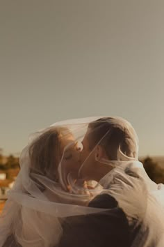 a bride and groom kissing under a veil