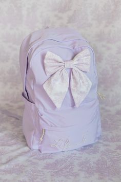 Size is approx.: 17"x12"x6.5"(L*H*D), ideal for a 15" laptop Lavender backpack with bow and pearl name.  Personalize this beautiful backpack with a name up to 8 letters.  Please allow 2-4 weeks for processing. Lavender Backpack, Pearl Name, Backpack Purple, Beautiful Backpacks, Purple Backpack, Backpack School, Purple Lavender, Backpack Purse, School Backpacks