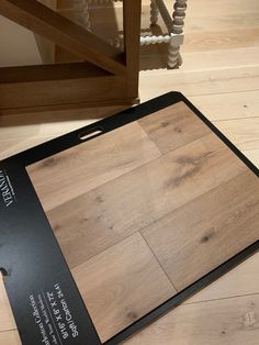 a wooden cutting board sitting on top of a hard wood floor next to a stair case