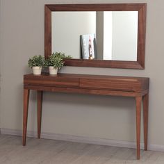 a wooden table with a mirror and potted plant