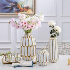 three vases with flowers in them sitting on a table