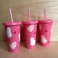 three pink cups with ghost designs on them