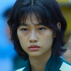 a close up of a person with freckles on their hair and wearing a green shirt