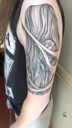 a woman's arm with a black and white tattoo design on her left shoulder