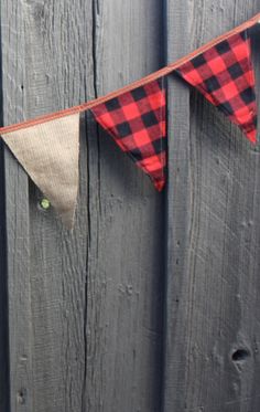 a red and black plaid bunting hanging on a wooden fence next to a tennis ball