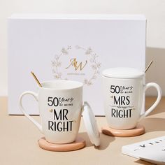 two coffee mugs sitting on top of a table next to a box with the word mr and mrs right