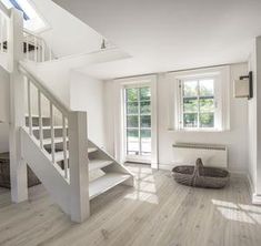 an empty room with white walls and wood flooring, stairs leading up to the second floor