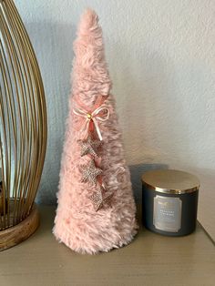 a pink christmas tree sitting on top of a wooden table next to a candle holder