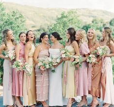 a group of women standing next to each other wearing dresses and holding bouquets in their hands