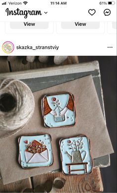 three decorated cookies sitting on top of a table next to a spool of thread