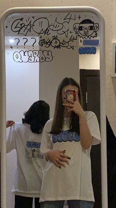 a woman taking a selfie in front of a mirror with graffiti on the wall