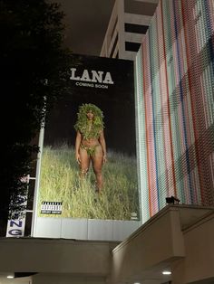 a large billboard on the side of a building with a woman's body covered in grass