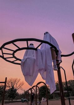 there are two cloths hanging from the top of a metal structure with trees in the background