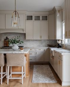 a kitchen with beige cabinets and white counter tops, an area rug on the floor