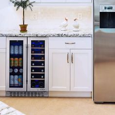 a stainless steel refrigerator and freezer combo in a white kitchen with marble counter tops