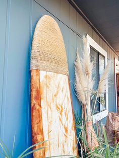 a surfboard leaning up against the side of a building with grass in front of it