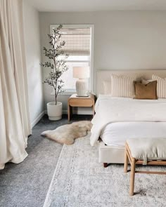 a bedroom with a bed, two nightstands and a rug on the floor in front of it