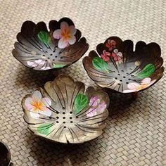 three metal bowls sitting on top of a table next to a bowl with flowers painted on it