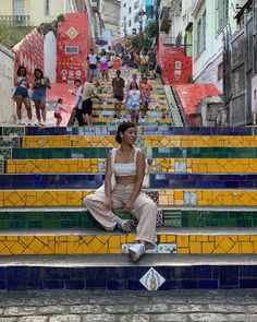 a woman sitting on the steps in front of some stairs with people walking up and down them