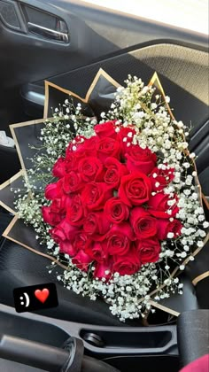 a bouquet of red roses sits in the center console of a car, surrounded by baby's breath