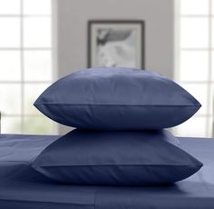 two blue pillows are stacked on top of each other