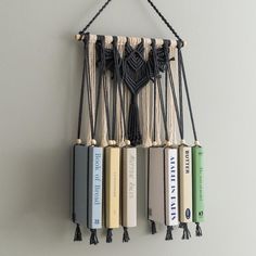 a wall hanging with books and tassels attached to it