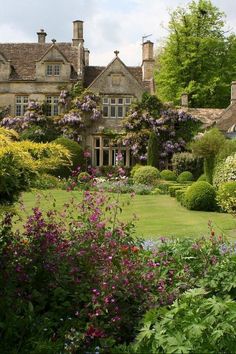 a large house surrounded by lush green trees and flowers