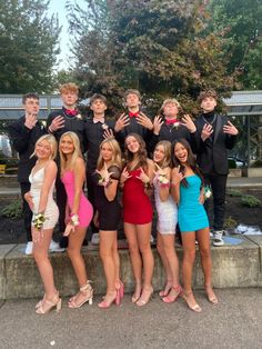 a group of young people standing next to each other in front of a fountain with their hands up